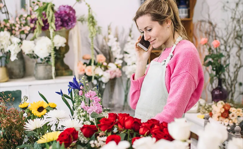 fleuriste en train de prendre une commande de fleurs par téléphone dans sa boutique de fleurs